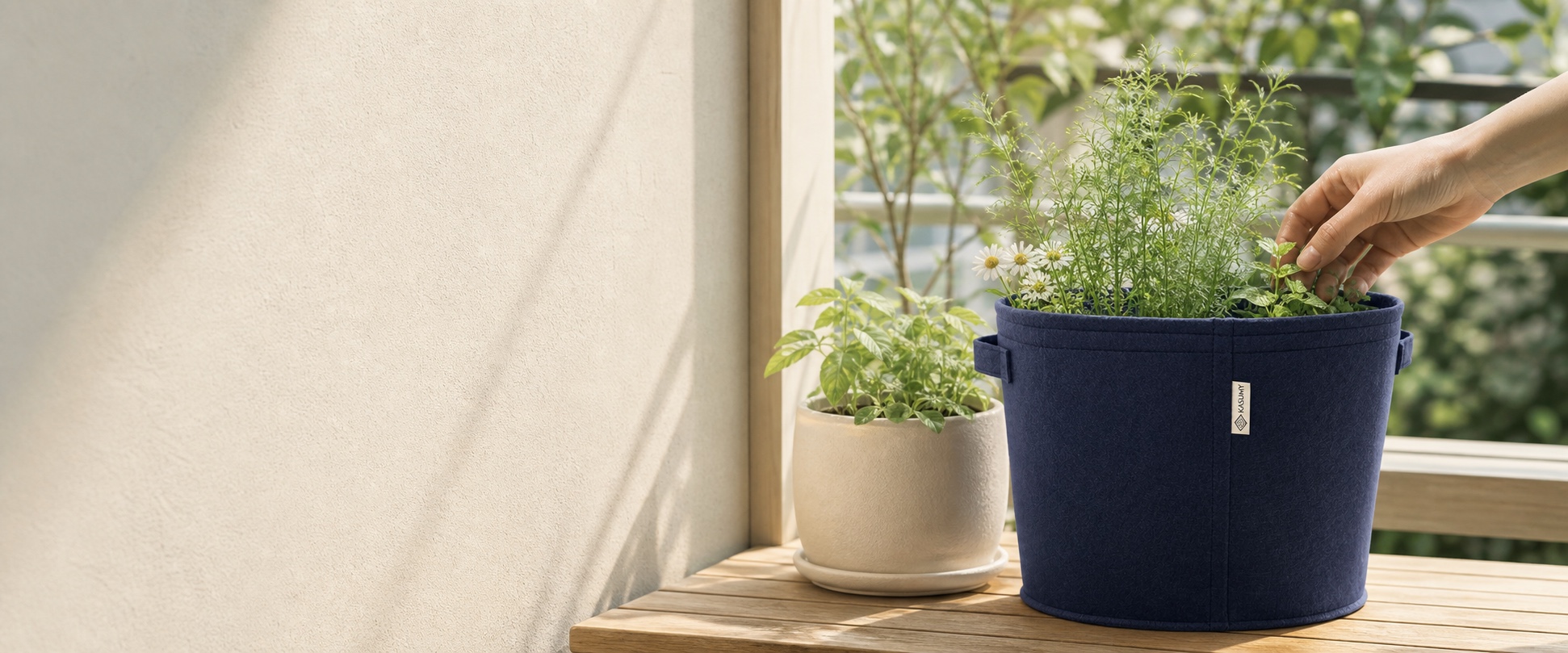 明るいバルコニーで、ネイビーのKASUMYエアリーポットに植えた植物を手入れする様子
